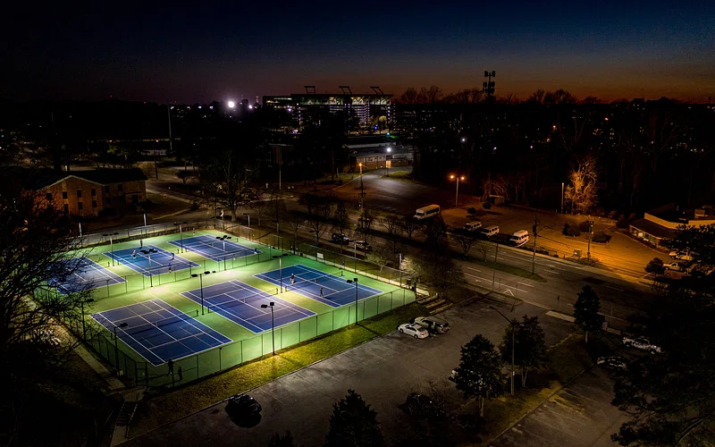 Quadras de tênis iluminadas à noite em ambiente urbano
